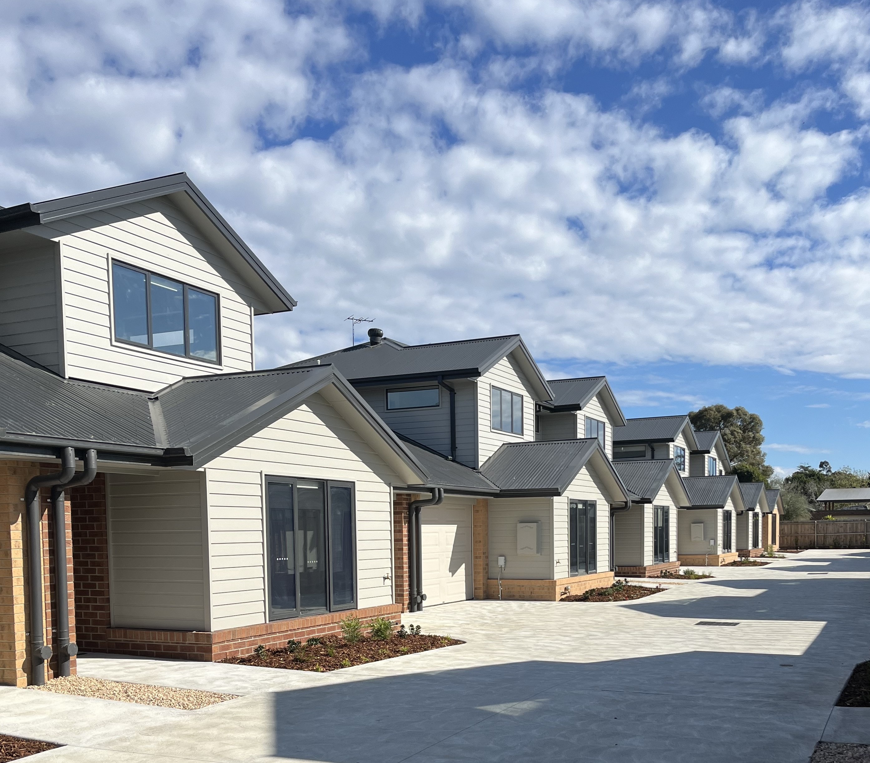 Pakenham social housing — white-clad townhouses with dark roofing